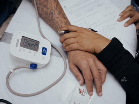 hand holds wrist of person having blood pressure taken on machine. only the hands and machine are visible