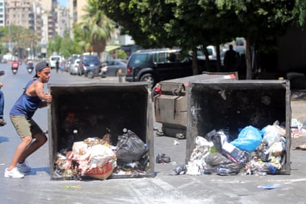 Protesters move a garbage container to block a main road in Beirut