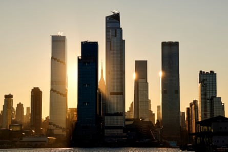 the sun rises behind buildings