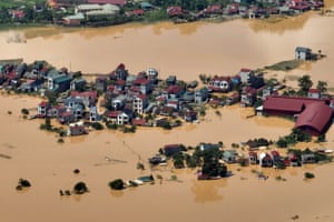 An aerial shot of a cluster of houses surrounded on all sides by muddy floodwater