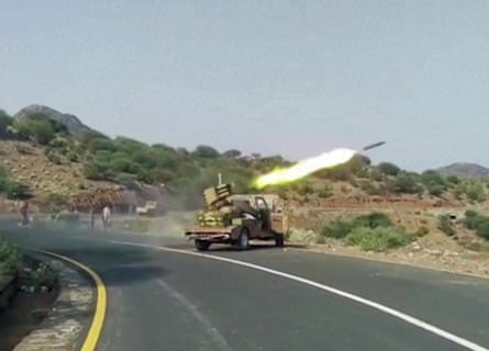 A rocket being fired from a vehicle-based launcher on a tarmac road
