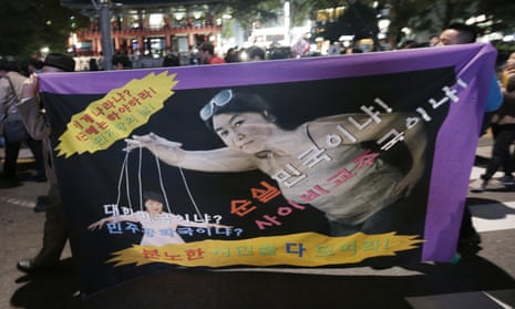 South Korean protesters carry a banner depicting President Park Geun-hye as a marionette and Choi Soon-sil as the puppeteer.