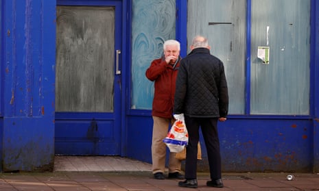 Two men talk outside an empty shop in Whitehaven