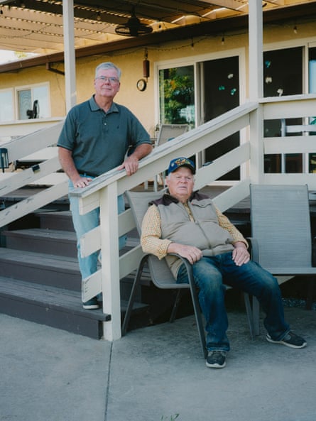 Two men pose for a portrait outside home