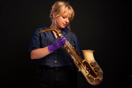 A woman wearing surgical gloves holds David Bowie’s first instrument, a Grafton Alto saxophone, dating from around 1961