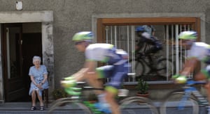 Riders are reflected in a window as they pass through a town
