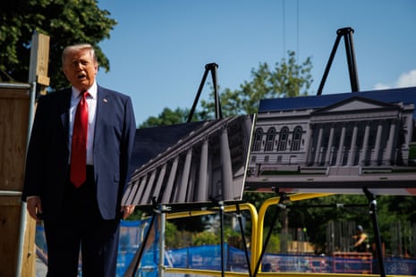 a man in a suit speaks next to displays for a proposed building