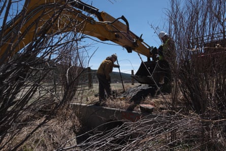 Workers with Pacheco Landscape Supply work on clearing an acequia in Holman, NM.