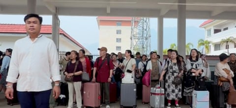 A crowd of people with luggage at a train station.