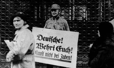 A Nazi soldier in Berlin holding a sign reading: ‘Germans! Defend Yourselves!, Don’t Buy From Jews!’ in 1933.