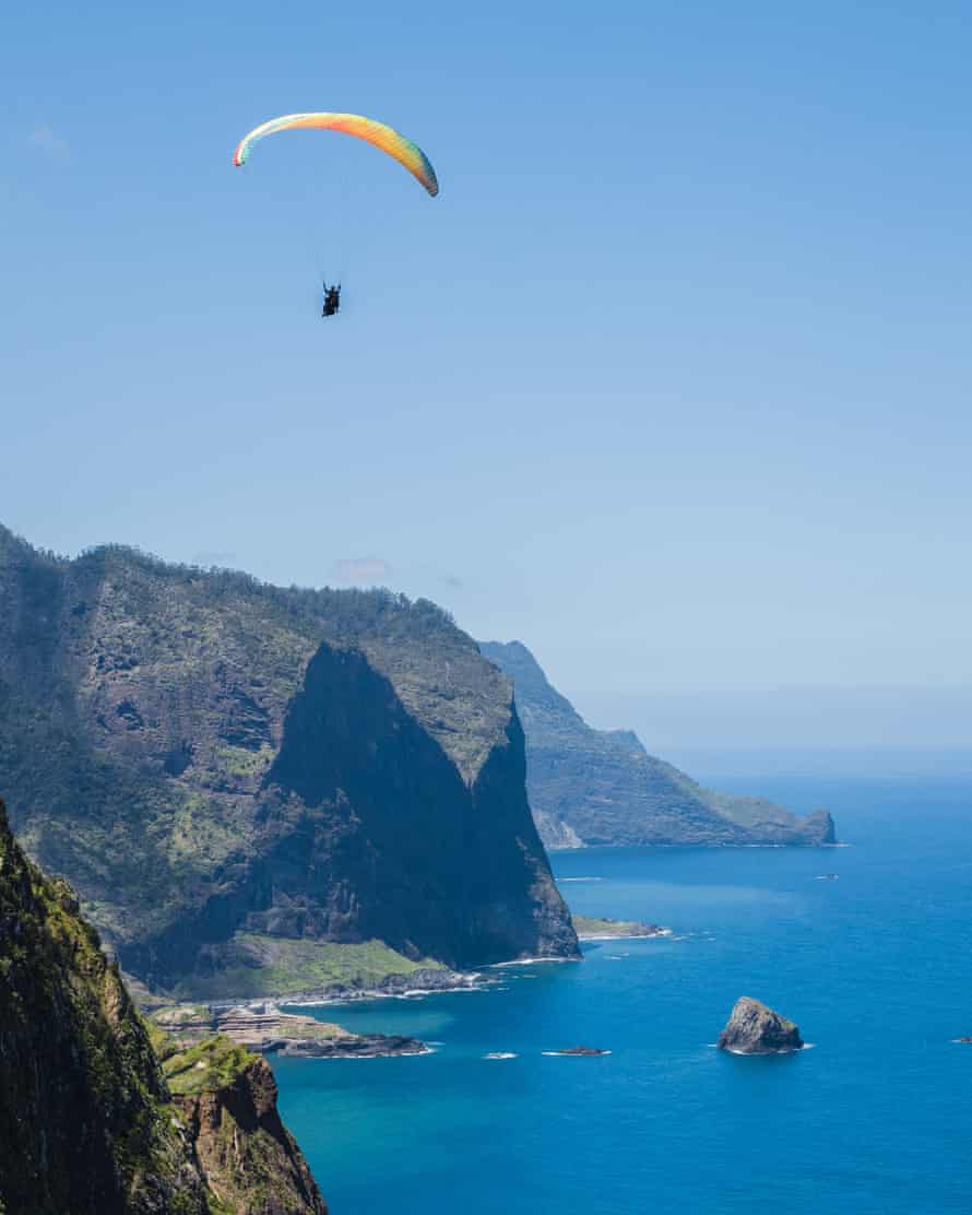 Glimpse of the paraglider flying over the village of Porto da Cruz with the Penha D'aguia mountain in the background on the island of Madeira.
