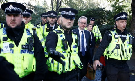 Police escort Michael Gove as he leaves parliament.