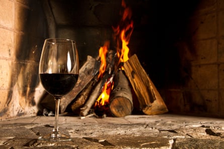 A glass of red wine in front of an open fire