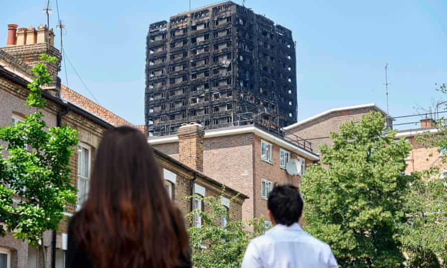 The burnt-out shell of Grenfell Tower is seen behind terraced houses.