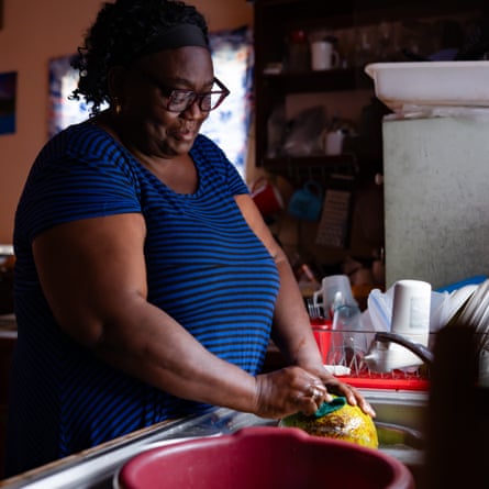 A woman stands at a sink washing up.