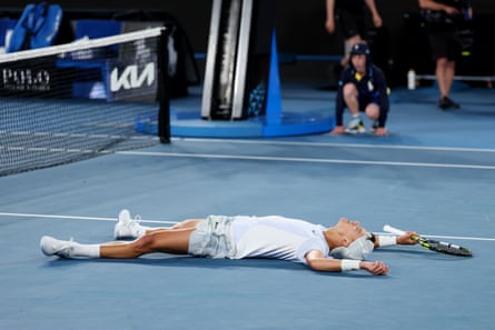 Rune lies flat on his back on a tennis court as he celebrates beating Miomir Kecmanovic of Serbia at the Australian Open