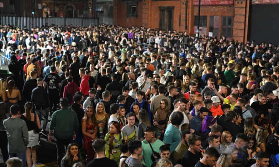 A huge throng of clubgoers waiting in an open area by an old building