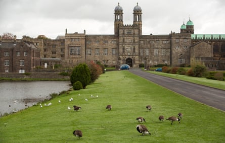 A grand building with green space and a lake in front
