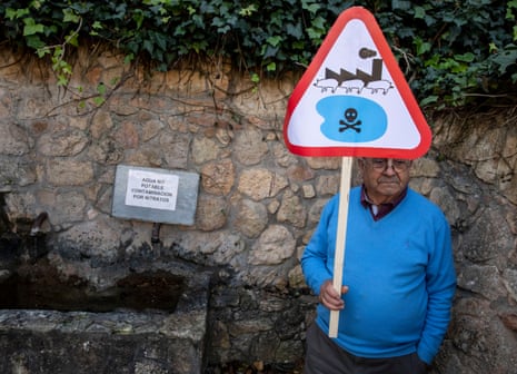 An activist holding a sign stands next to a contaminated water source in Balsa de Ves.