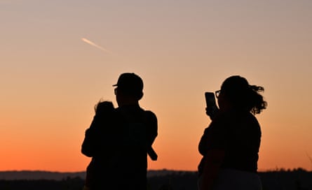Silhouette of two adults, one holding a child, just after sunset