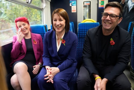 Haigh, Reeves and Burnham smile as they sit alongside each other on a local train