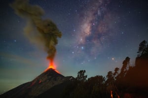 Milky Way above an erupting volcano