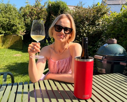 Mina Holland seated at a garden table raising a glass of wine with the Yeti Rambler wine cooler.