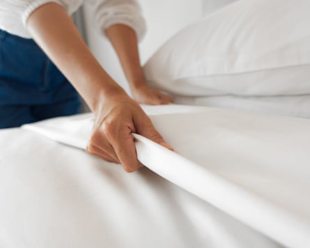 A hand on white bed sheet in bedroom