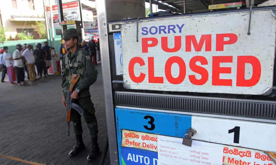 A Sri Lankan security official stands guard outside a fuel station that ran out of petrol in Colombo, Sri Lanka on Monday.