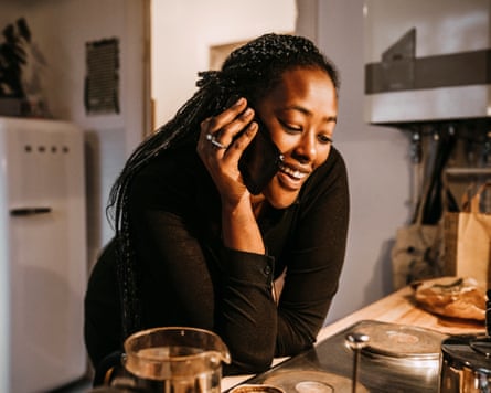 A woman at a kitchen counter, talking on the phone.