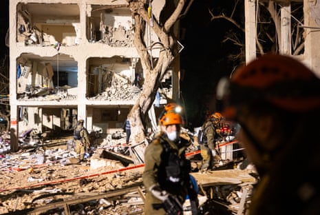 Emergency workers gather in the early hours of March 22, 2026 at the site of an Iranian missile strike hours earlier in Arad, Israel.