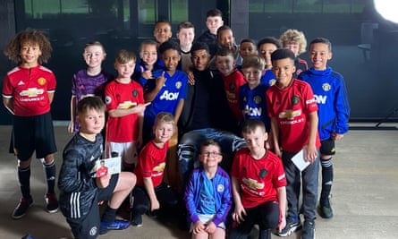 Marcus Rashford poses with a gorup of children after a press conference