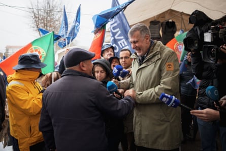 Man surrounded by people and press microphones.