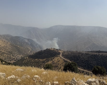 Smoke rises from a hillside in a parched-looking landscape