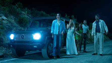 Five young people, three female, two male, look in horror at something unseen, on a deserted road at night outside a Mercedes G-Wagon with its headlights on.