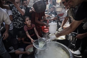 People reach out and hold containers as food is dished out
