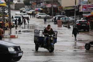 Palestinians walk in a street flooded by rain water in Dair Al Balah in the central of Gaza Strip. The bad weather and snow has caused damage to homes, mainly in the Gaza Strip, and forced the government and banks to call off work.