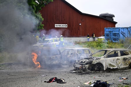 Police stand near the gutted remains of cars in Stockholm after an Eritrean festival that turned violent in August