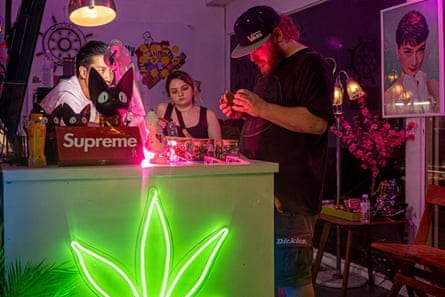 Tourists look at cannabis products while a retailer watches