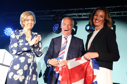 Three people smiling on stage with a Union flag