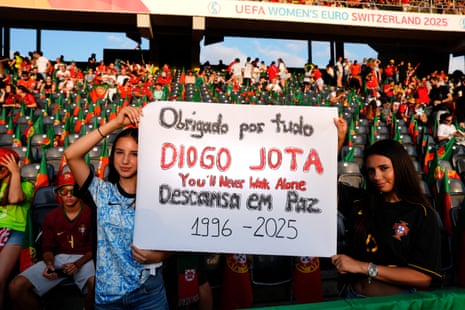 A pair of Portugal fans in Bern hold up a tribute to Diogo Jota, who died alongside his brother Andre Silva in a car accident in Spain this morning.