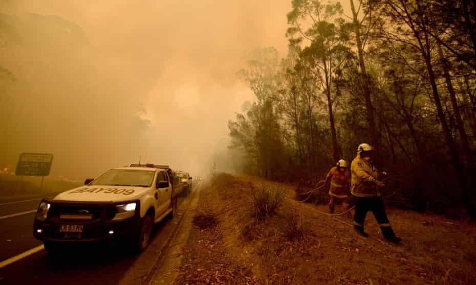 Firefighters tackle a bushfire in thick smoke in the New South Wales town of Moruya