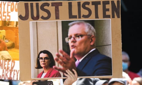 A placard of Scott Morrison with Anne Ruston in the background and the words “just listen”