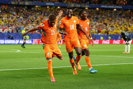 Amad Diallo wearing an orange Côte d’Ivoire jersey celebrates after scoring a goal.
