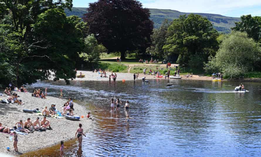 People relax on the banks and paddle in the River Wharfe in Ilkley.