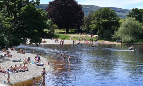 People relax on the banks and swim in the River Wharfe in Ilkley.