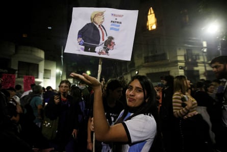 A woman holds a sign critical of the Trump-Milei relationship