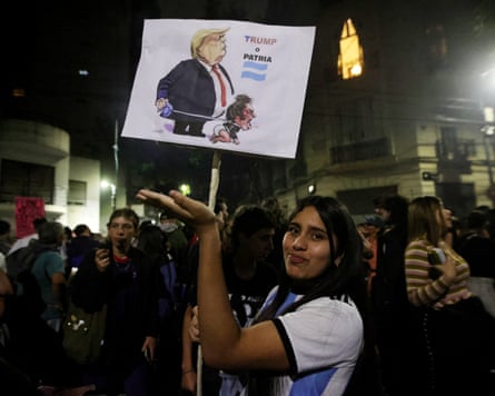 A demonstrator holds a sign depicting Donald Trump and Javier Milei.
