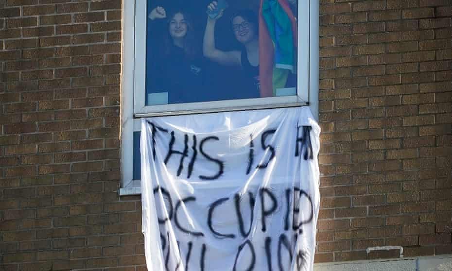 Manchester University students gesture at window