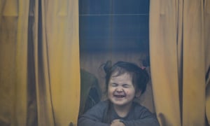 A child refugee fleeing the war from neighboring Ukraine with her family reacts as she sits in a bus after crossing the border by ferry at the Isaccea-Orlivka border crossing, in Romania, Friday, March 25, 2022. (AP Photo/Andreea Alexandru)